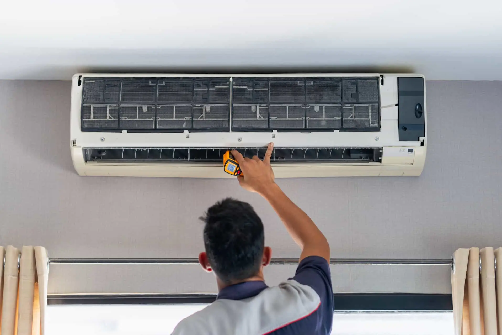 Technicien en train de vérifier et installer un climatiseur dans une maison, assurant le bon fonctionnement d'une pompe à chaleur air-air.