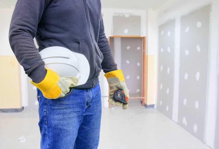 Technicien portant un casque de protection et des gants, préparant un diagnostic personnalisé dans un intérieur en cours de rénovation, pour évaluer les besoins en isolation thermique