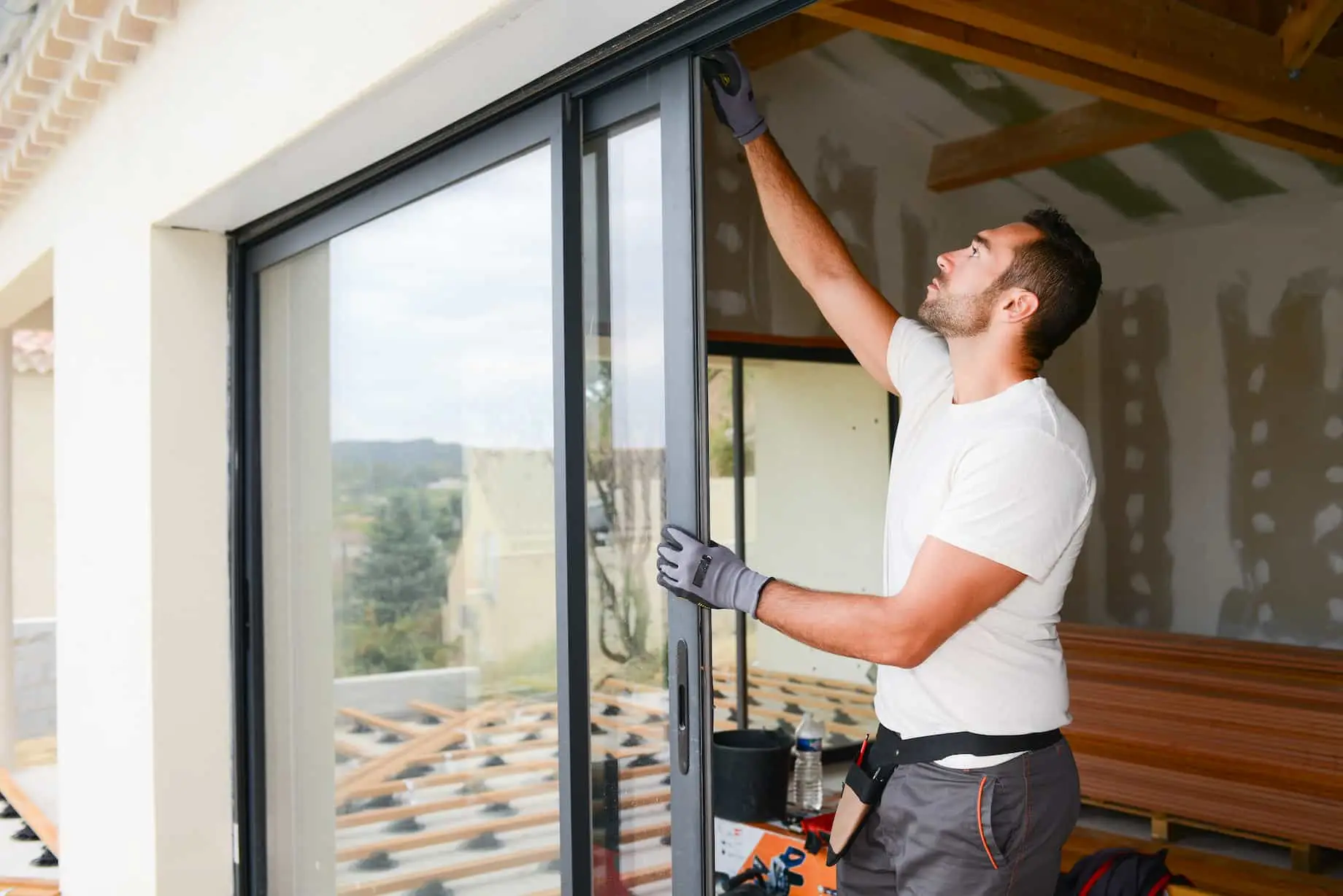 Technicien installant une porte coulissante pour améliorer l'isolation d'une maison.