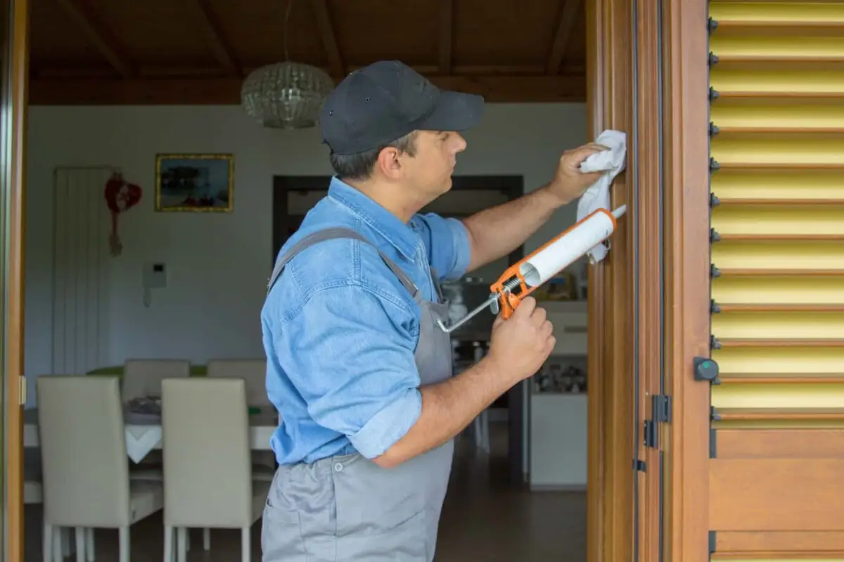 Technicien appliquant un joint d'étanchéité lors de l'installation d'une porte pour améliorer l'isolation