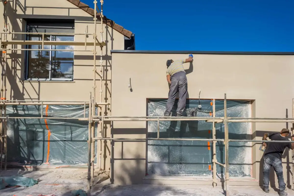 Ouvriers réalisant l'isolation thermique des murs extérieurs d'une maison à l'aide d'échafaudages