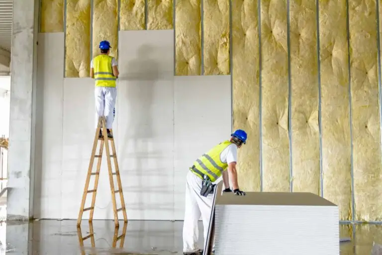 Ouvriers installant des plaques de plâtre sur des murs isolés avec de la laine minérale pour une isolation thermique intérieure