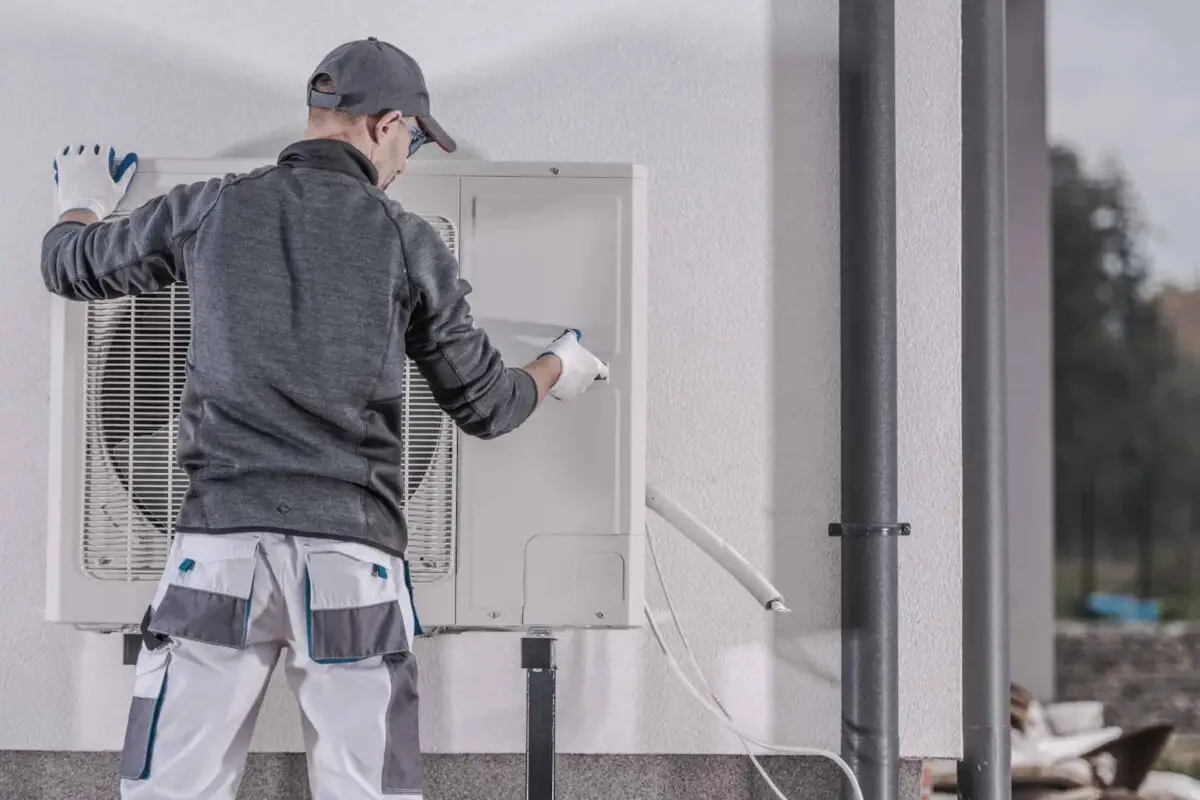 Technicien effectuant l'installation ou l'entretien d'une pompe à chaleur air-eau sur une maison, optimisant son efficacité pour le chauffage.