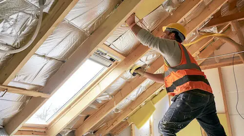 Artisan de Groupe APB installant de l'isolation dans des combles aménageables pour améliorer l'efficacité énergétique.