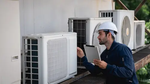 Technicien inspectant une installation de pompe à chaleur air-eau. Solution de chauffage écologique et économe en énergie.